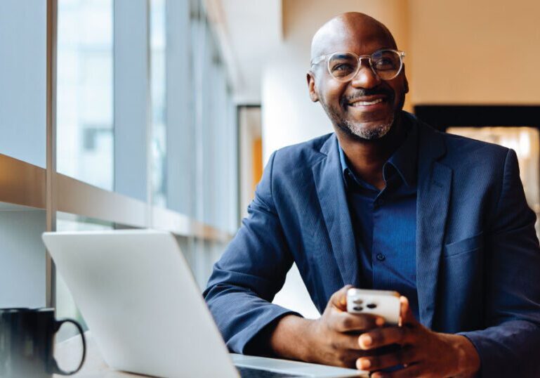 A business professional sitting at a desk with a laptop and phone, representing corporate leadership and board governance protected by D&O liability insurance.