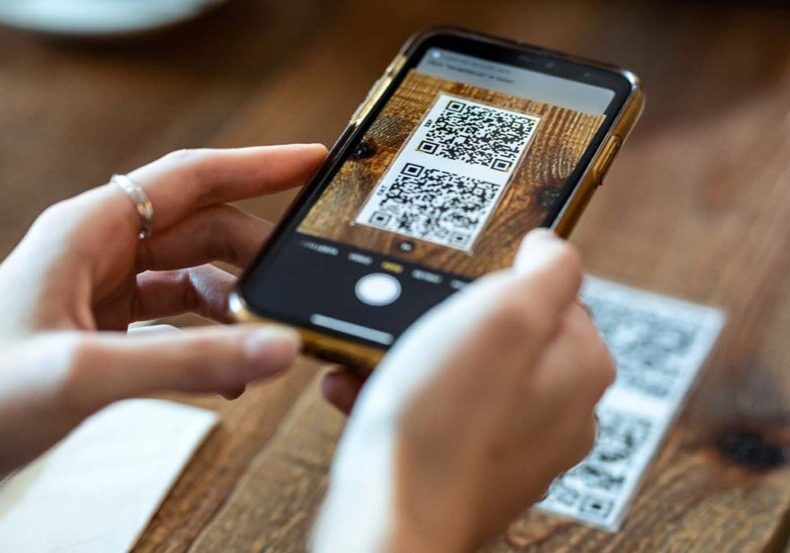 Close up of young woman hands using the smart phone to scan the qr code to select food menu in the restaurant.