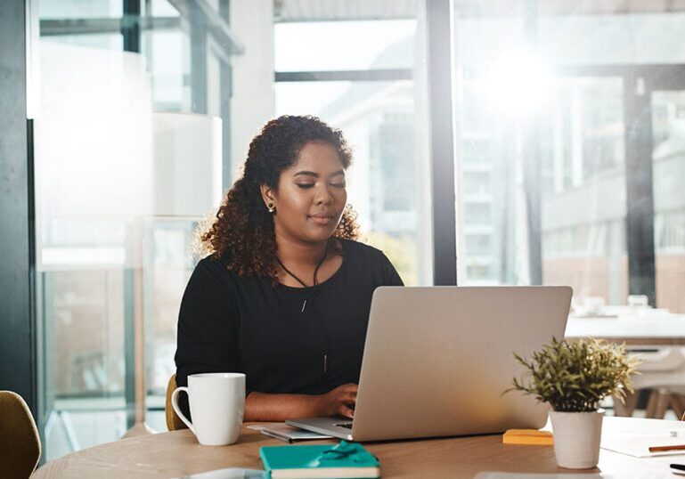 Woman working on a laptop in an office reviewing an email to identify potential phishing scams